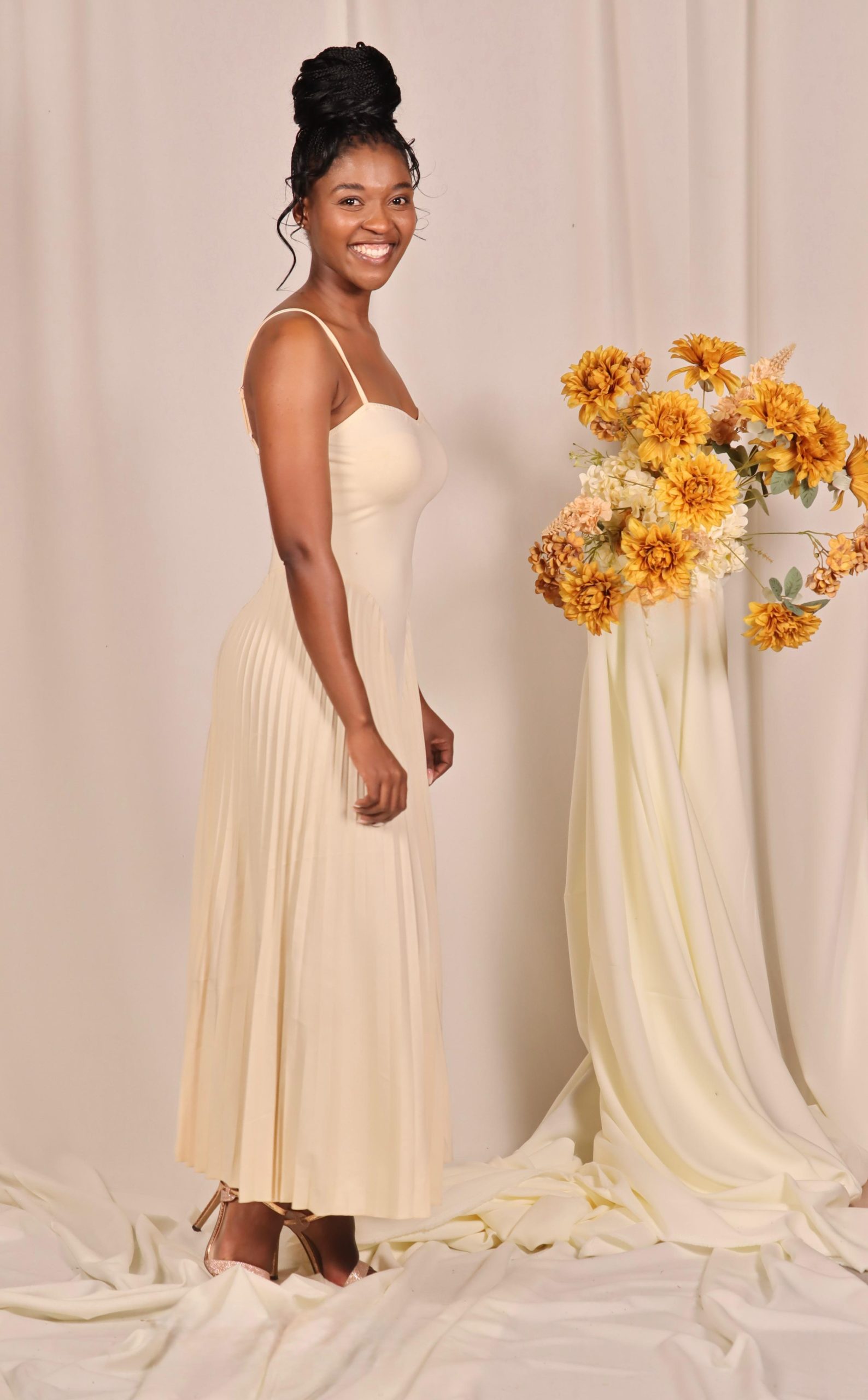 Reabetswe Redavicca Morake in a cream dress beside golden flowers